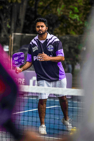 Man holding PInaka Lavender picleball paddle on a pickleball court