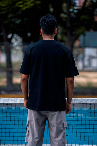 a man viewed from behind standing on a pickleball court,