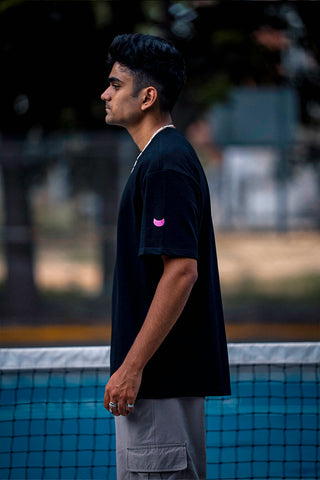 A man in a black t-shirt standing on a pickleball court.