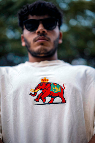 A man wearing a beige shirt with an elephant print on the front standing on a pickleball court