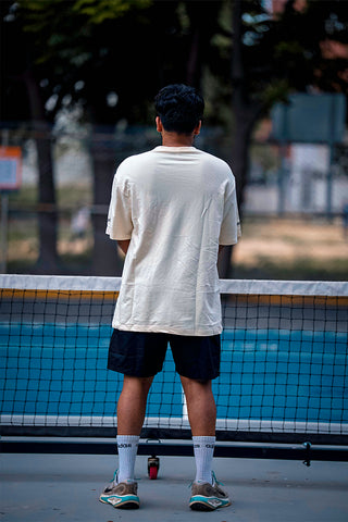 A man wearing a beige shirt  standing on a pickleball court