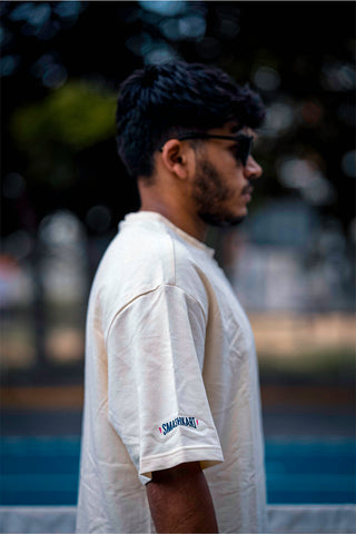 A man wearing a beige shirt with an elephant print on the front standing on a pickleball court